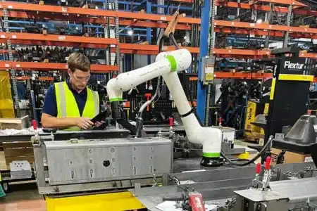 5 Unexpected Welding Automation Benefits That Can Transform Your Business shown through a worker using a cobot on a Flextur table